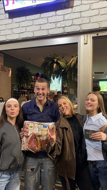 Friends holding a Bells Meats prize pack at Hey Darl