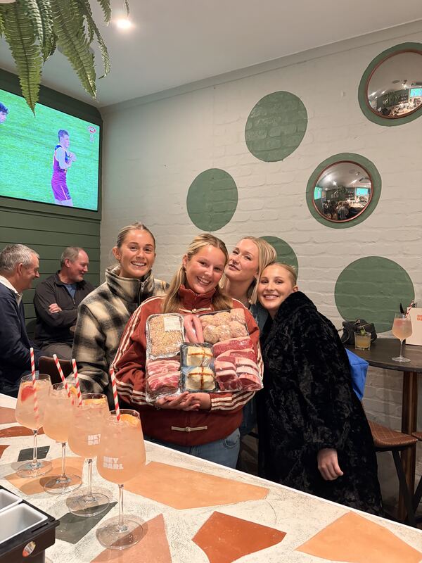 Friends holding a Bells Meats prize pack at the bar